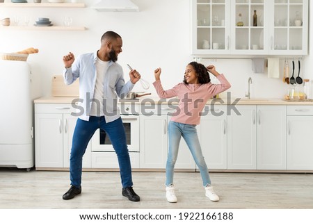 Playful Mood. Excited African American father and joyful girl dancing while cooking together at kitchen, fooling around, cheerful man holding whisk, spending free time with cute daughter Royalty-Free Stock Photo #1922166188