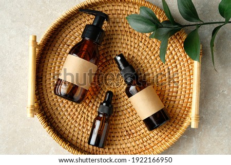 Amber glass cosmetic bottles set in rattan container on table in bathroom. SPA natural organic beauty products for personal hygiene, toiletry cosmetics. Royalty-Free Stock Photo #1922166950