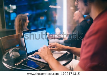 Cropped male freelancer checking program text on blank laptop computer with copy space area for internet advertising,unrecognizable man connecting to public wireless for browsing web on mockup netbook