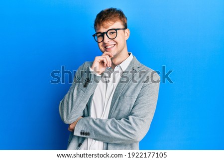 Young caucasian man wearing elegant clothes and glasses looking confident at the camera with smile with crossed arms and hand raised on chin. thinking positive.  Royalty-Free Stock Photo #1922177105