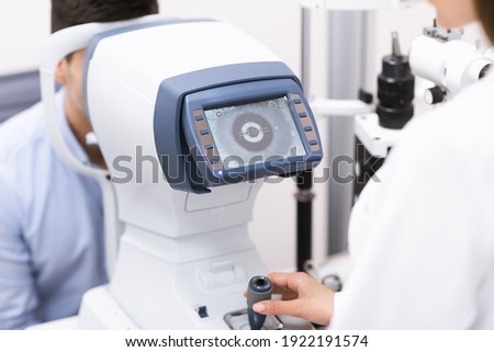 Ophthalmic Exam Concept. Ophthalmologist checking vision of young male patient in clinic with auto refractometer, using modern equipment, closeup. Eye examination for glasses or lenses prescription Royalty-Free Stock Photo #1922191574