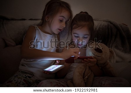 Little girls watching smartphone in bed, kids using phone and play game, using mobile, addicted game and cartoon.