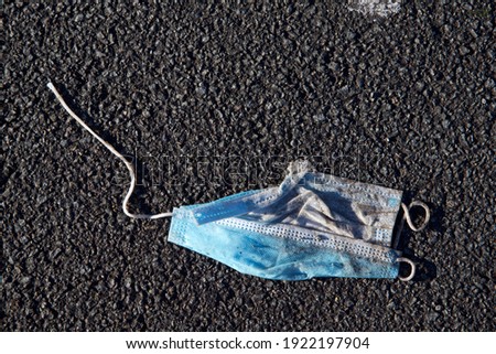 Face mask: a discarded, used anti-Covid face mask on a asphalt road surface