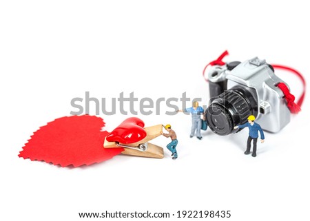 selective focus of miniature worker with plastic camera toy on white background.