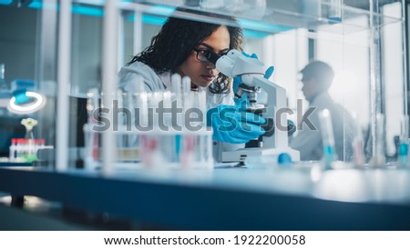 Medical Science Laboratory: Portrait of Beautiful Black Scientist Looking Under Microscope Does Analysis of Test Sample. Ambitious Young Biotechnology Specialist, working with Advanced Equipment Royalty-Free Stock Photo #1922200058
