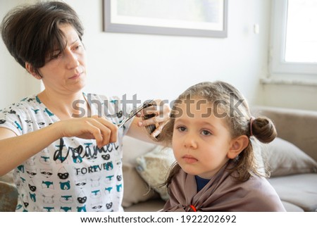 young woman is cutting her daughter's hair at home during the pandemic. stay at home.