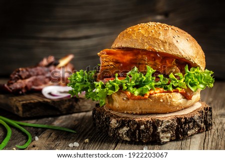Homemade burger with grilled ribs, vegetables, sauce on rustic wooden background. fast food and junk food concept.