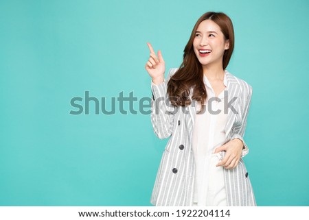 Young Asian woman smiling and pointing finger to empty copy space isolated on green background Royalty-Free Stock Photo #1922204114