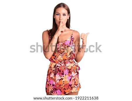 Young beautiful hispanic woman wearing casual clothes asking to be quiet with finger on lips pointing with hand to the side. silence and secret concept. 