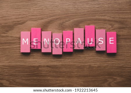 A pink wooden block with a text of menopause on wooden background. Royalty-Free Stock Photo #1922213645