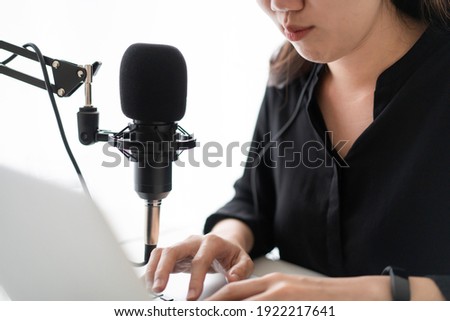 Beautiful and good looking young Asian woman arranging home podcast channel. Businesswoman recording her podcast for her online podcast live on the laptop computer and tablet. Modern working lifestyle