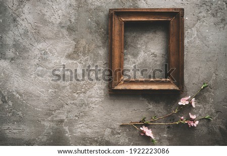 Vintage old wooden frame with spring flowers and leaves on dark rustic wooden background. Spring flowers composition with copy space.