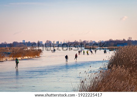 Ice skaters on lake "Rottemeren" in the western part of Holland during a cold spell in winter. In the distance the skyline of the city of Rotterdam is visible.