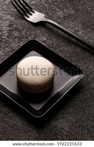 white macaroon cake in a square plate. stylish minimalistic close-up photo. Black fork, graphic food photo in dark colors, vertical arrangement. a concept for advertising a coffee shop or dessert