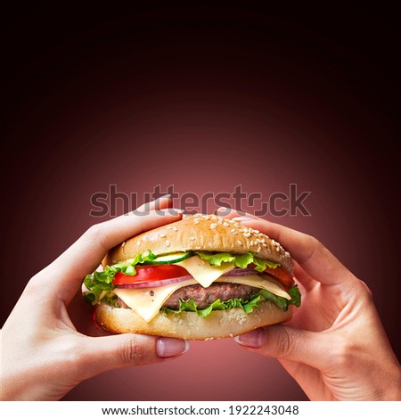 Hand holding a burger in a darkbackground. Eating and healthy concept, restaurant food concept. Royalty-Free Stock Photo #1922243048
