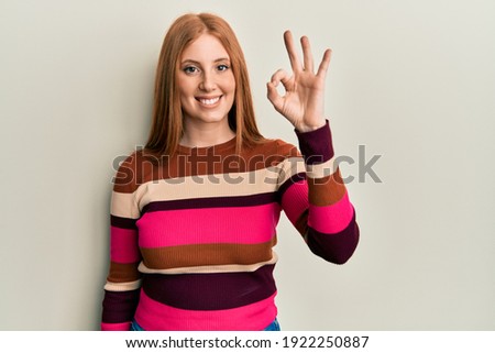 Young irish woman wearing casual clothes smiling positive doing ok sign with hand and fingers. successful expression. 