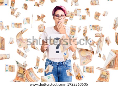 Young beautiful woman with pink hair holding question mark covering mouth with hand, shocked and afraid for mistake. surprised expression