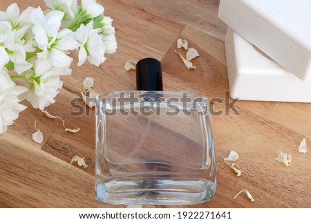 Perfume with white soap and flower in transparent bottle on wooden background.