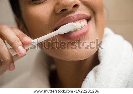 Cropped view of the portrait of a young smiling girl cleaning her teeth, while looking at the bathroom mirror. Lifestyle, beauty concept photo. Stock photo