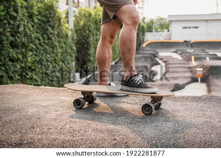 Closeup Asian man holding surfskate or skate board in pumptrack skate Park when sunrise time over photo blur of pumptrack curve, extream sport, healthy and exercise, fashion in covid19 concept