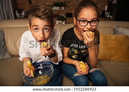 Cute children watching movie on TV on sofa in evening