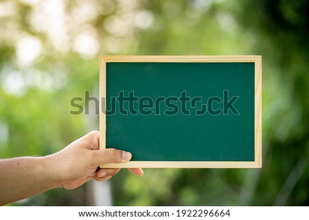 Man hand holding show a label wood board on sunlight in the public park, Copy space for advertising and announce concept.