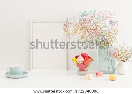 Sweet colorful macarons and flower gypsophila with white frame on table. 