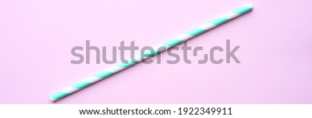 one paper striped white and green drinking straw for party on pink background. space for text. banner