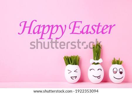 Funny handmade eggs with hair of green grass with copy space. Easter concept on pink backgrund, top view