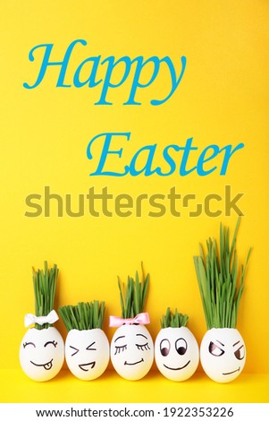 Funny handmade eggs with hair of green grass with copy space. Easter concept on yellow backgrund, top view