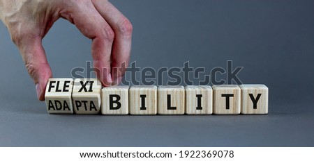 Flexibility and adaptability symbol. Businessman turns wooden cubes and changes words 'adaptability' to 'flexibility'. Grey background, copy space. Business, flexibility and adaptability concept. Royalty-Free Stock Photo #1922369078