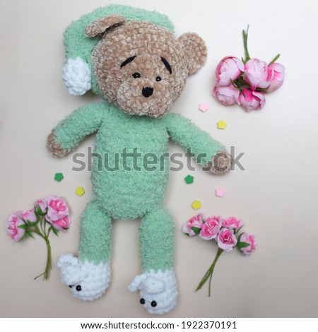 Handmade knitted toy. Knitted bear and flowers on light background. High quality photo