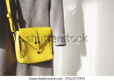 Fashion woman yellow bag and casual grey dress on white wall background with shadow. Trendy Color of Year 2021. Illuminating Yellow and Ultimate Gray. Copy space. Stylish casual female clothes set.