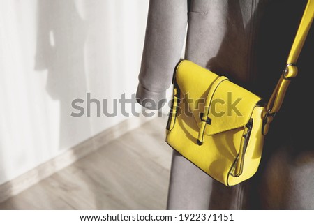 Fashion woman yellow bag and casual grey dress on white wall background with shadow. Trendy Color of Year 2021. Illuminating Yellow and Ultimate Gray. Copy space. Stylish casual female clothes set.