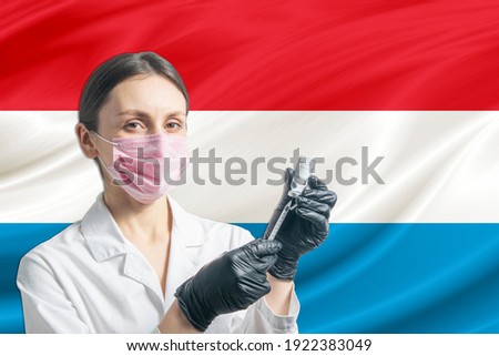 Girl doctor prepares vaccination against the background of the Luxembourg flag. Vaccination concept Luxembourg.