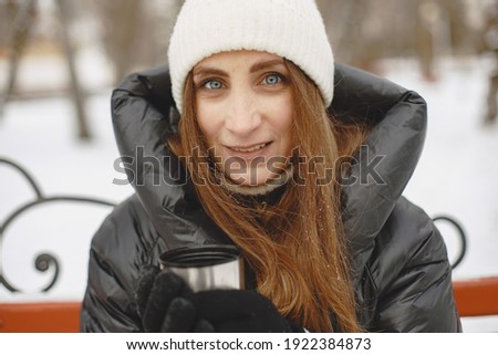 Lady with thermos. Girl drinks tea. Woman in a black jacket.