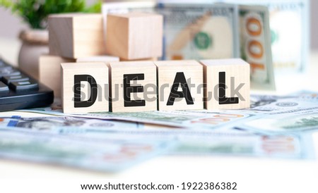 The word DEAL on wood cubes, banknotes and calculator on the background. Business and finance concept.