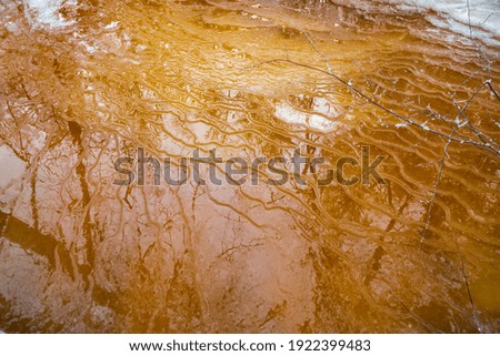 Drawings of winter on the frozen river, the reflection of trees on an ice smooth surface, the wild frozen small river in the winter wood, the wild nature at sunset, the river of red color, ice