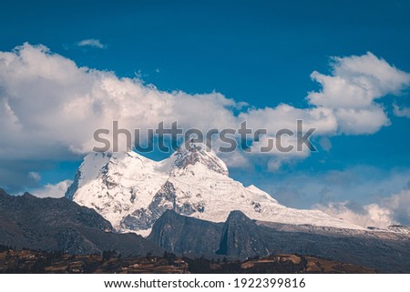 Nevado Huandoy surrounded by clouds above the mountains Royalty-Free Stock Photo #1922399816