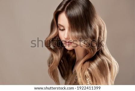 Beauty  girl with long  and   shiny wavy  Hair ,coloring and toning, shatush and balayash .  Beautiful   woman model with curly hairstyle . Royalty-Free Stock Photo #1922411399