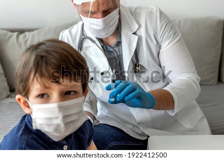 Selective focus of a doctor with syringe doing injection of vaccine to male patient wearing face protective medical mask for protection from virus disease. Medicine, vaccination and healthcare concept