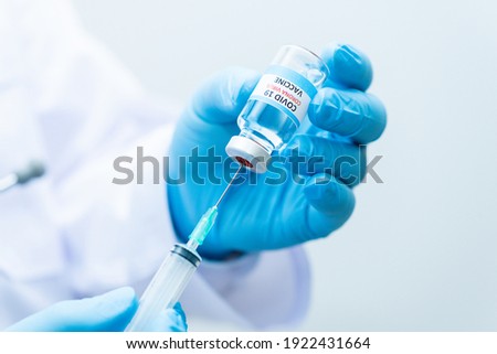 Doctor wearing blue gloves is holding  virus vaccine Corona  and syringes