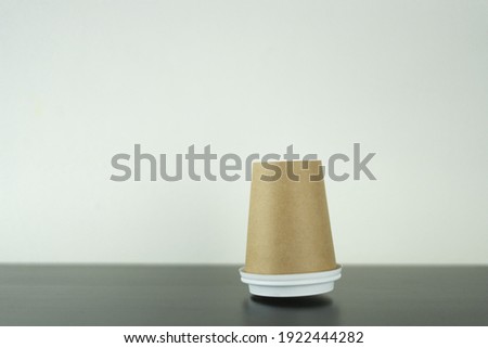 a takeaway paper cup in mid-air is falling on the wooden table upside down. This photo is suitable for use as a mockup to put your logo or design