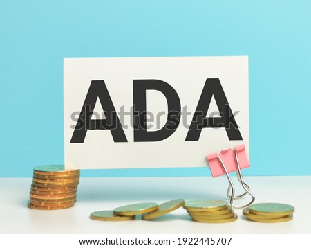 Business and finance concept. Phrase ADA written on white card with coins.