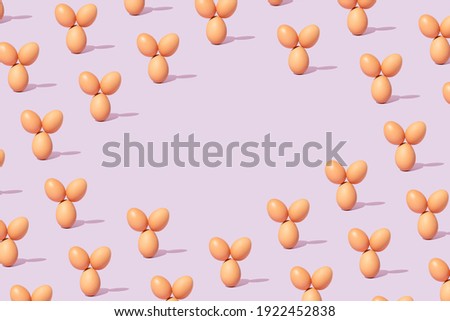 Creative pattern made with easter eggs against purple background. Eggs arranged like they have ears. Minimal food layout with copy space.