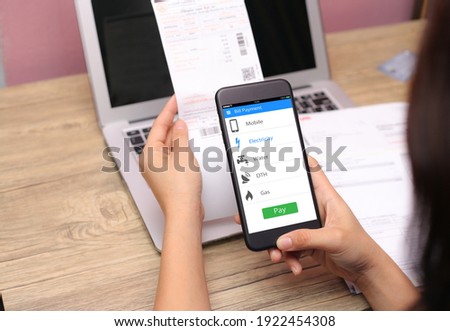 Online bill payment concept.Hands holding mobile phone on blurred Electric bill as background Royalty-Free Stock Photo #1922454308