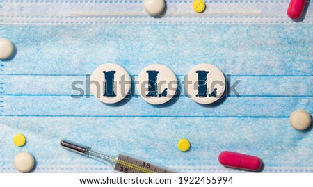 There are wooden cubes with the word ILLNESS and a stethoscope on a wooden background. Medical concept