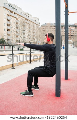 young boy training legs in a park with red headphones