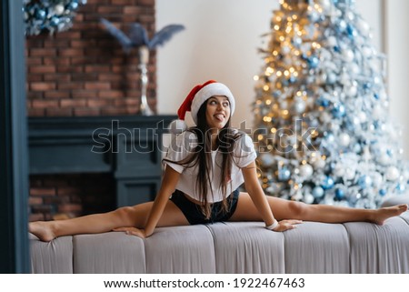 Young beautiful woman practicing split near the christmas tree