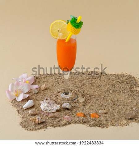 Orange cocktail arranged on the sand. Decorated with sea shells. Creative idea.